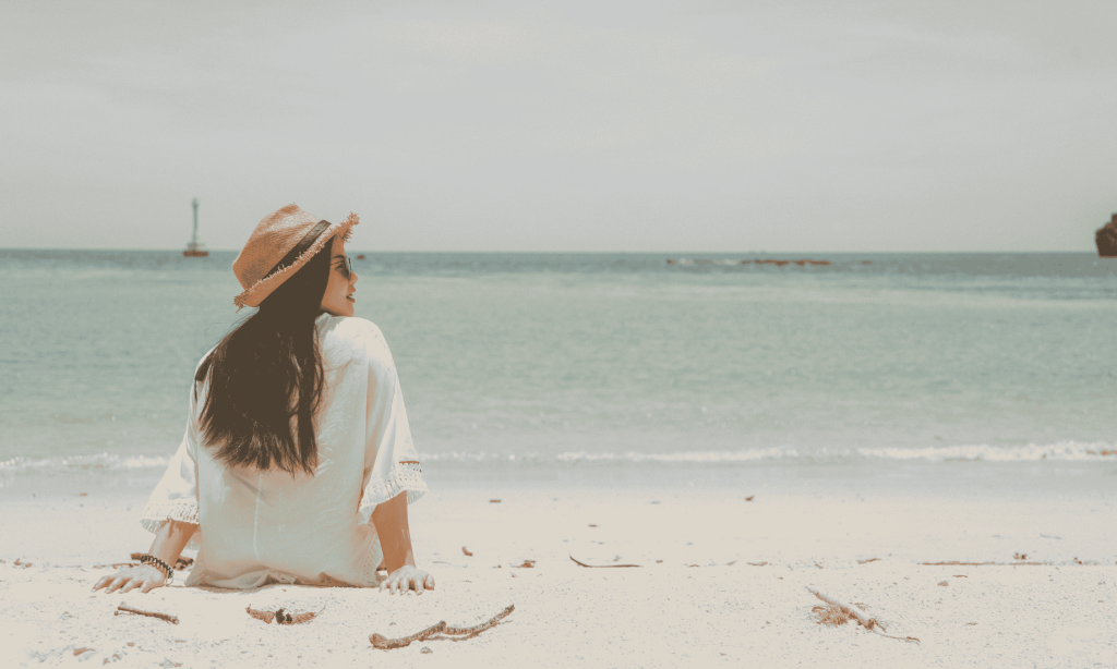 A girl wearing a hat sitting on the beach