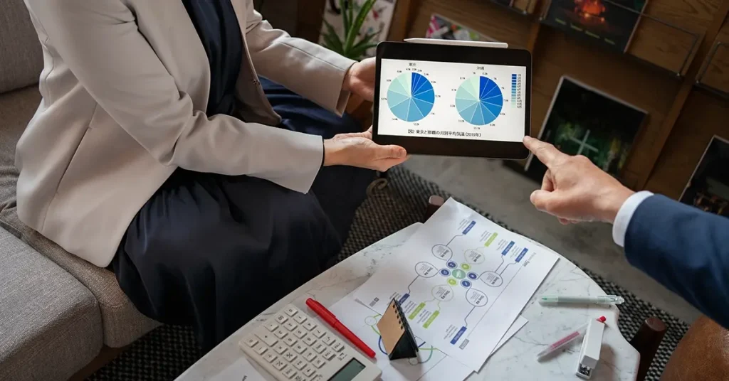 A close-up of a person holding a gold credit card while working on a laptop at a wooden desk.